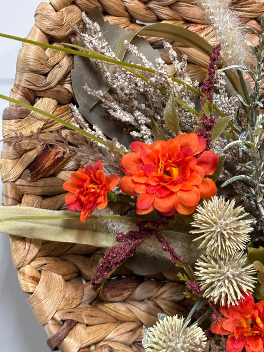 Woven pumpkin door hanger featuring a gingham bow and autumn flowers in orange and neutral tones.