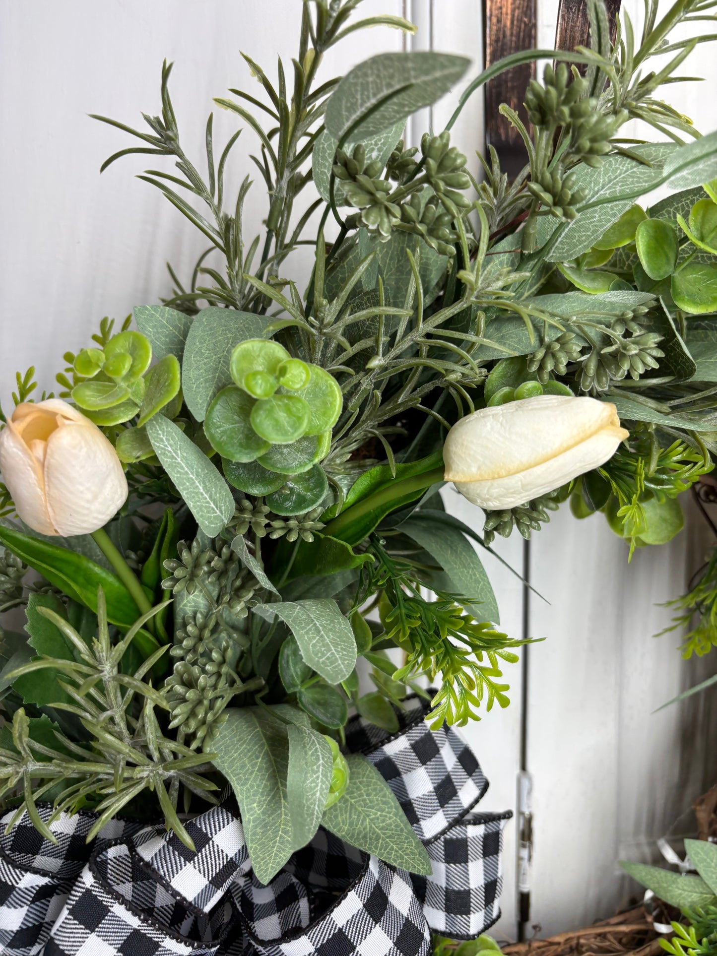 Spring tulip wreath featuring cream tulips, eucalyptus, and a black and white checkered bow on a grapevine base.