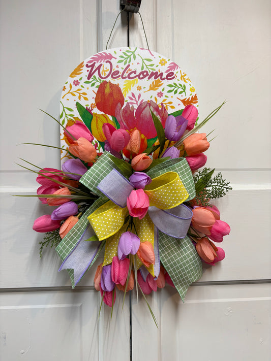 Spring tulip sign door hanger with pink, purple, and orange tulips, featuring a welcome message and decorative ribbons.