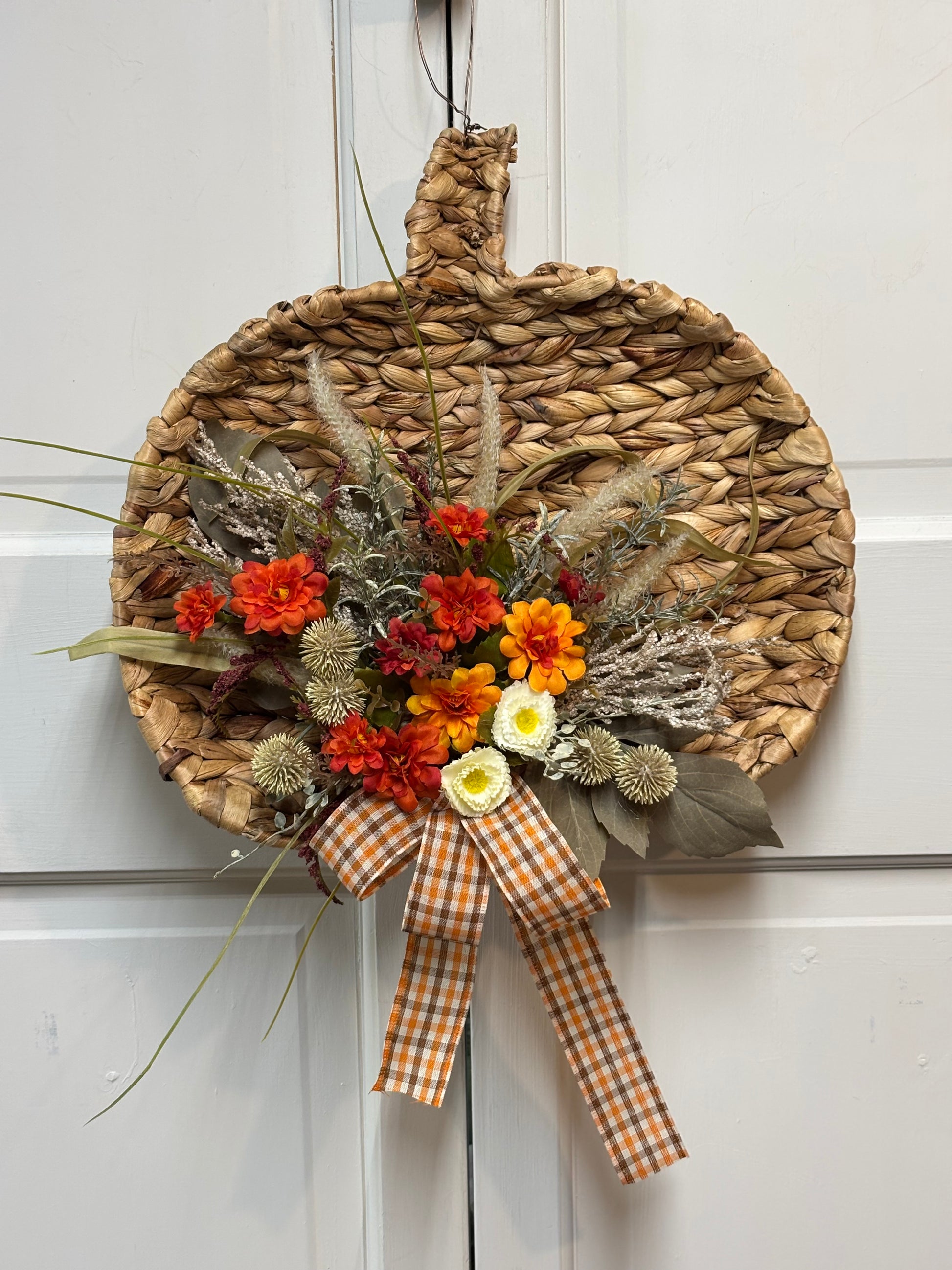 Woven pumpkin door hanger with a gingham bow and colorful floral accents, measuring 15 inches for fall decor.
