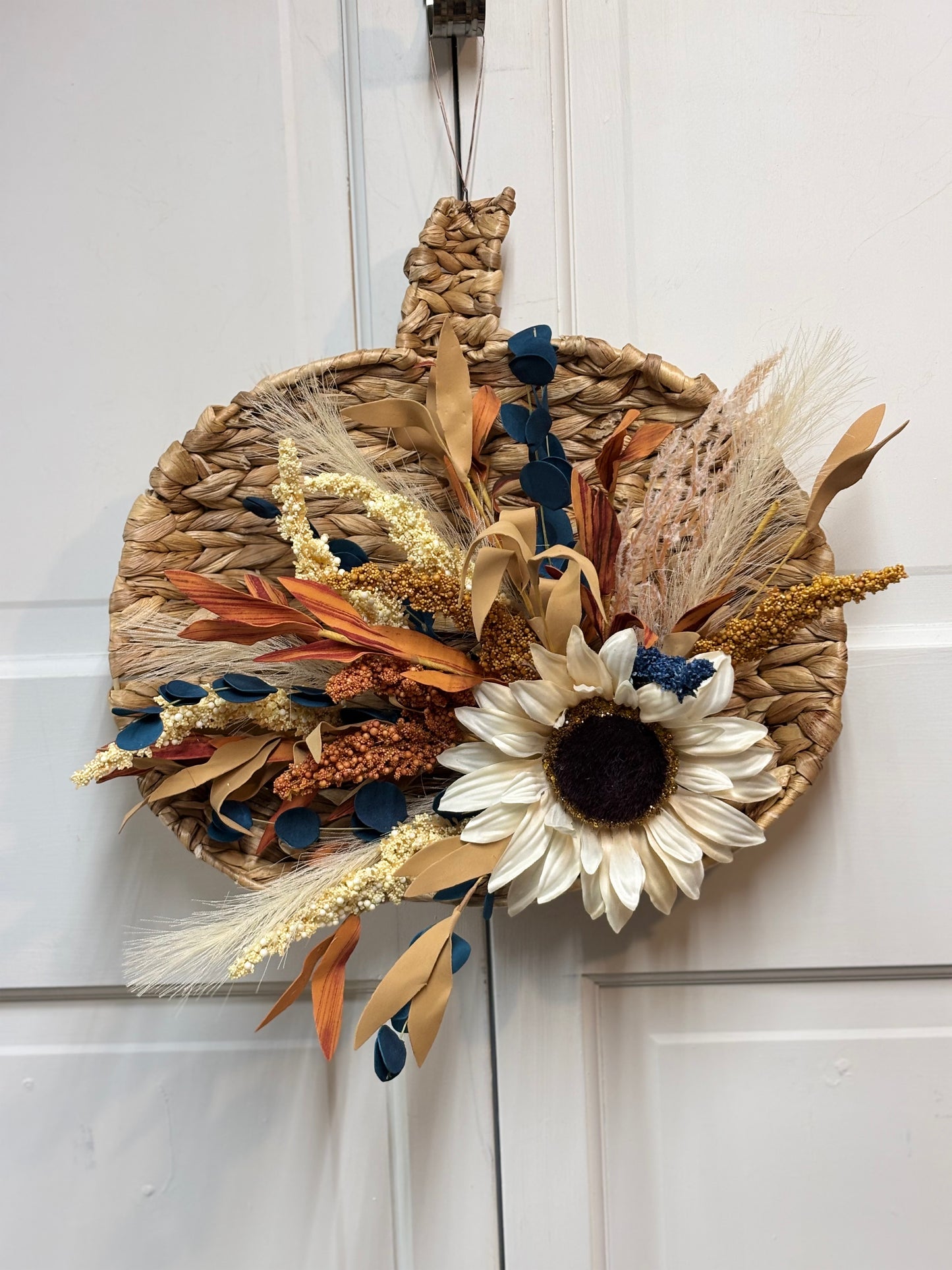 Woven pumpkin door hanger featuring a sunflower and autumn foliage in warm tones, measuring 15 inches.